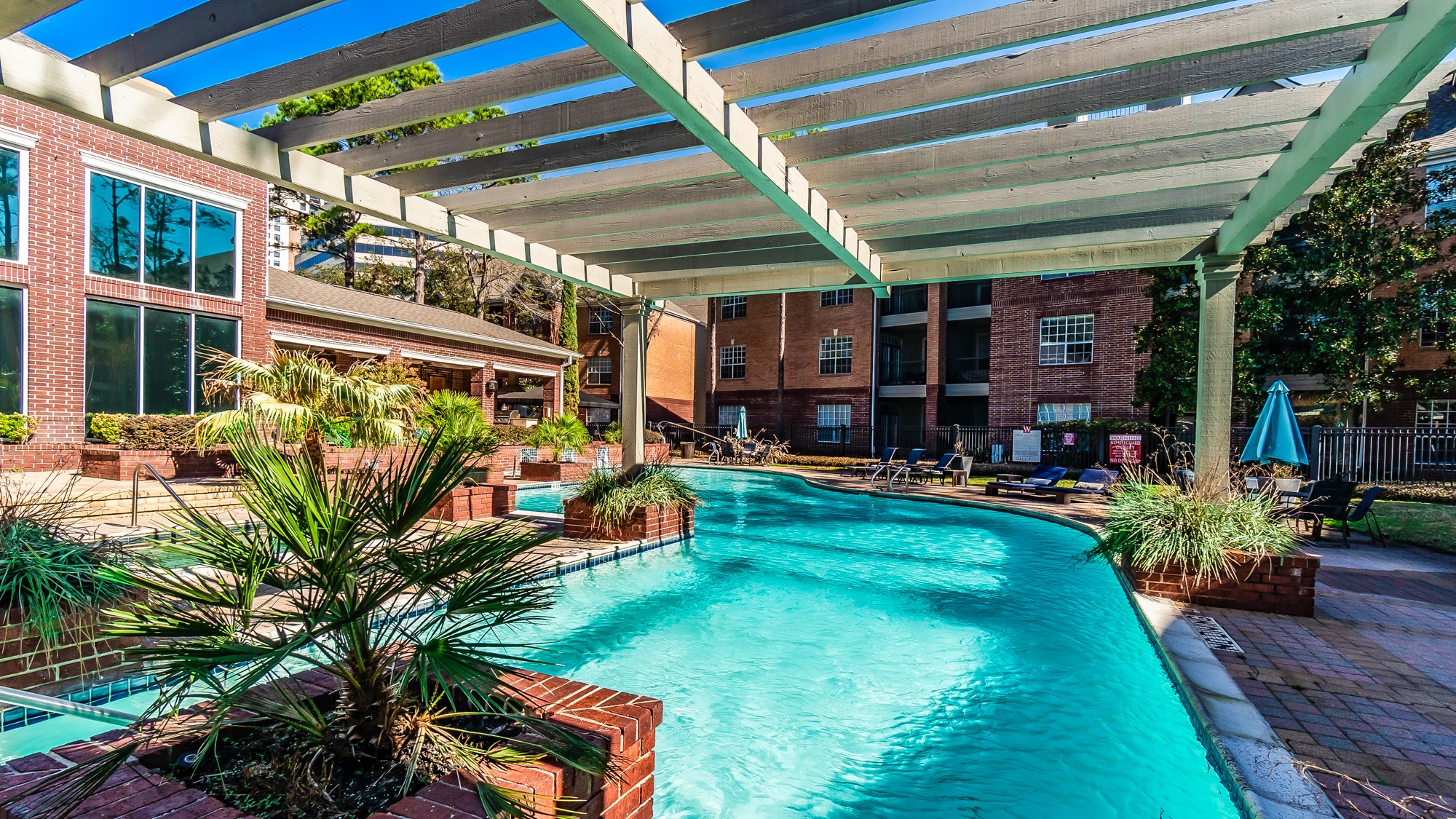 A pool under a white canopy with a building in the background.